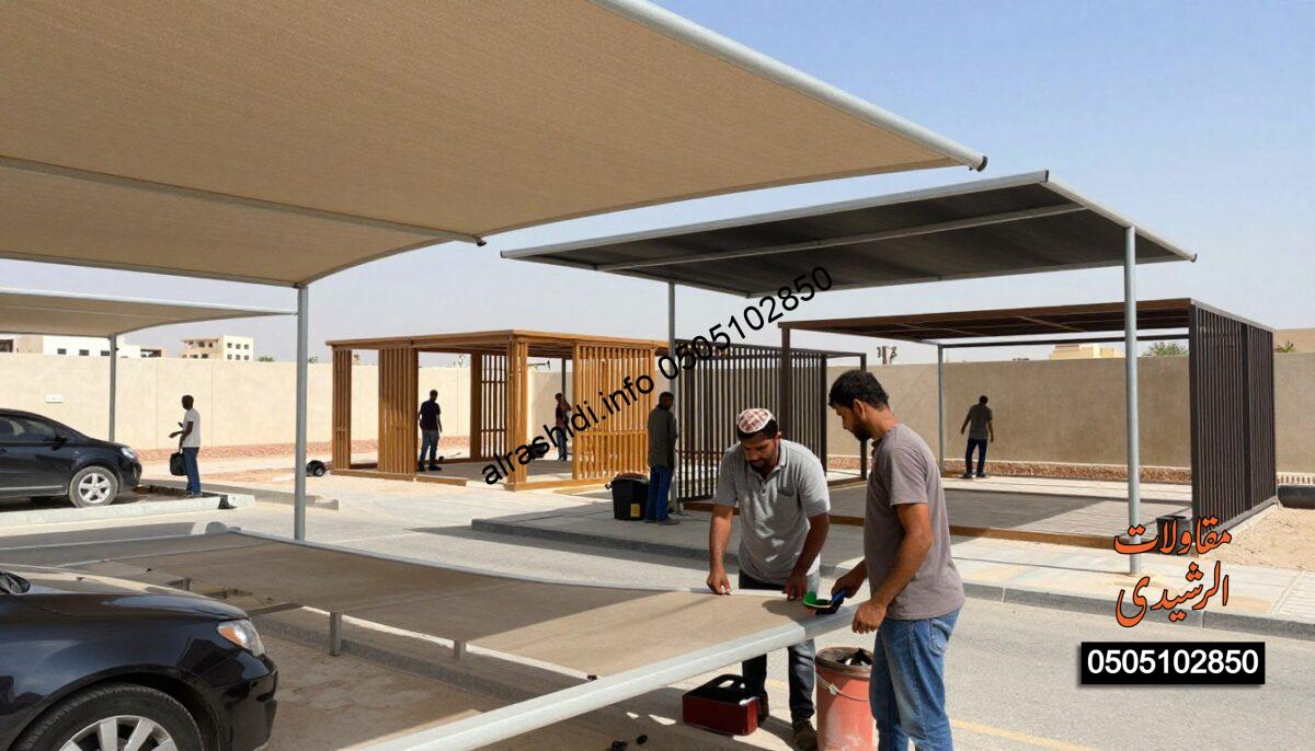 A realistic construction scene depicting workers installing various shades in South Riyadh, showcasing fabric, metal, and wooden structures. In the foreground, two workers in modest casual clothing are focused on installing a large fabric shade over a car parking area, tools in hand. In the middle ground, additional workers are seen assembling wooden and metal structures for garden and school shades, surrounded by a variety of partially erected shade designs. The background features a sunny blue sky with a hint of distant residential buildings typical of South Riyadh. The scene conveys a sense of professionalism and collaboration under natural daylight, with soft shadows enhancing the details of the shades being constructed.