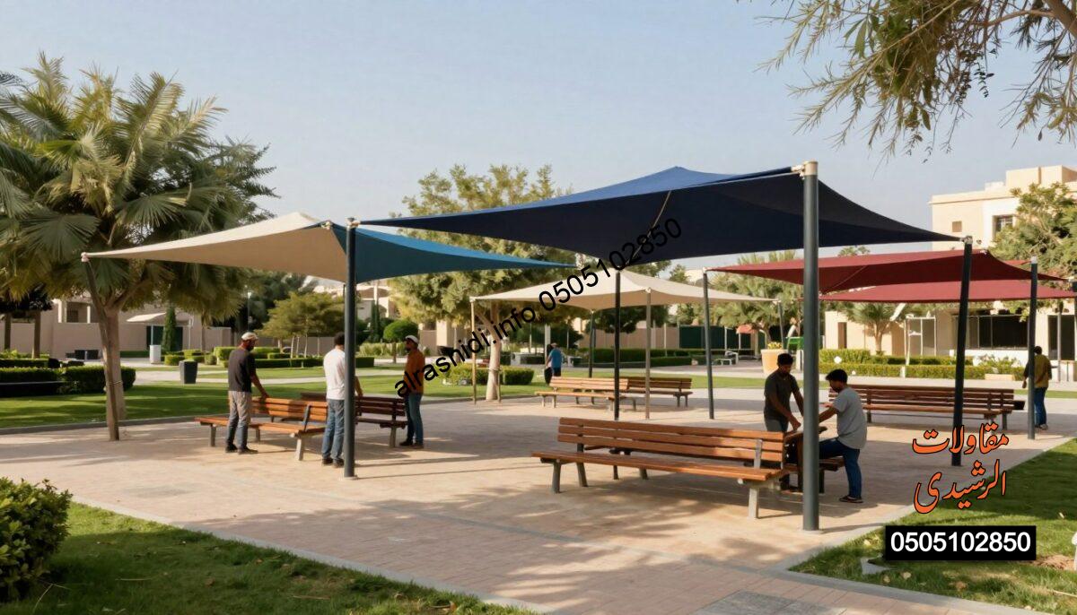 A vibrant outdoor scene showcasing a variety of garden and public amenities canopies in a beautiful park setting in northern Riyadh. In the foreground, skilled workers in modest casual clothing are diligently installing large, colorful shades above picnic areas, ensuring ample protection from the sun. The middle ground features a mix of elegantly designed canopies draping over benches and trees, reflecting a harmonious blend of functionality and style. The background showcases lush greenery and clear blue skies, enhancing the tranquil atmosphere. Soft, warm sunlight filters through the canopies, creating playful shadows on the ground. The image should be captured from a slightly elevated angle to provide a comprehensive view, emphasizing the installation process and the beauty of the shaded areas in this public space.